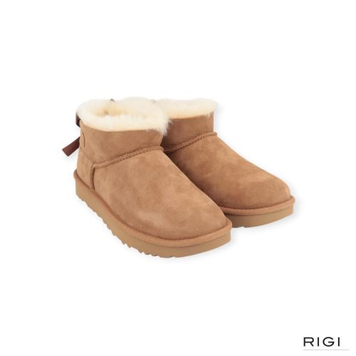 Ugg Ultra Mini Bailey Bow enkellaars in cognac, chestnut suède met wol en strik voor dames. Ugg Ultra Mini Bailey Bow enkellaars in cognac, chestnut suède met wol en strik voor dames.