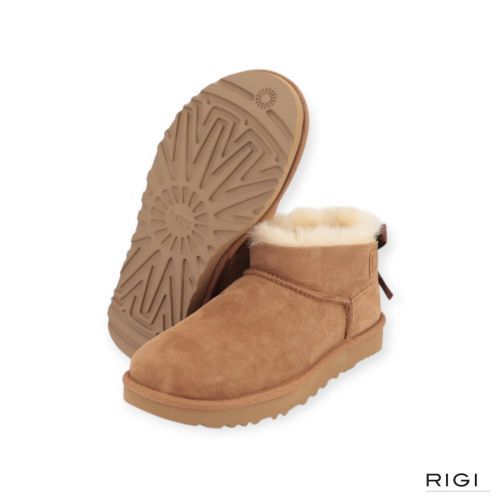 Ugg Ultra Mini Bailey Bow enkellaars in cognac, chestnut suède met wol en strik voor dames. Ugg Ultra Mini Bailey Bow enkellaars in cognac, chestnut suède met wol en strik voor dames.
