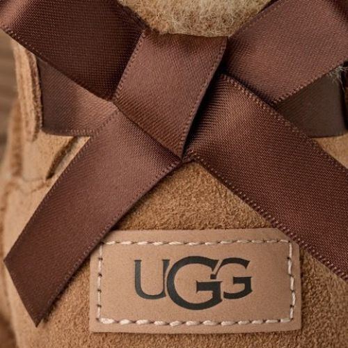 Ugg Ultra Mini Bailey Bow enkellaars in cognac, chestnut suède met wol en strik voor dames. Ugg Ultra Mini Bailey Bow enkellaars in cognac, chestnut suède met wol en strik voor dames.